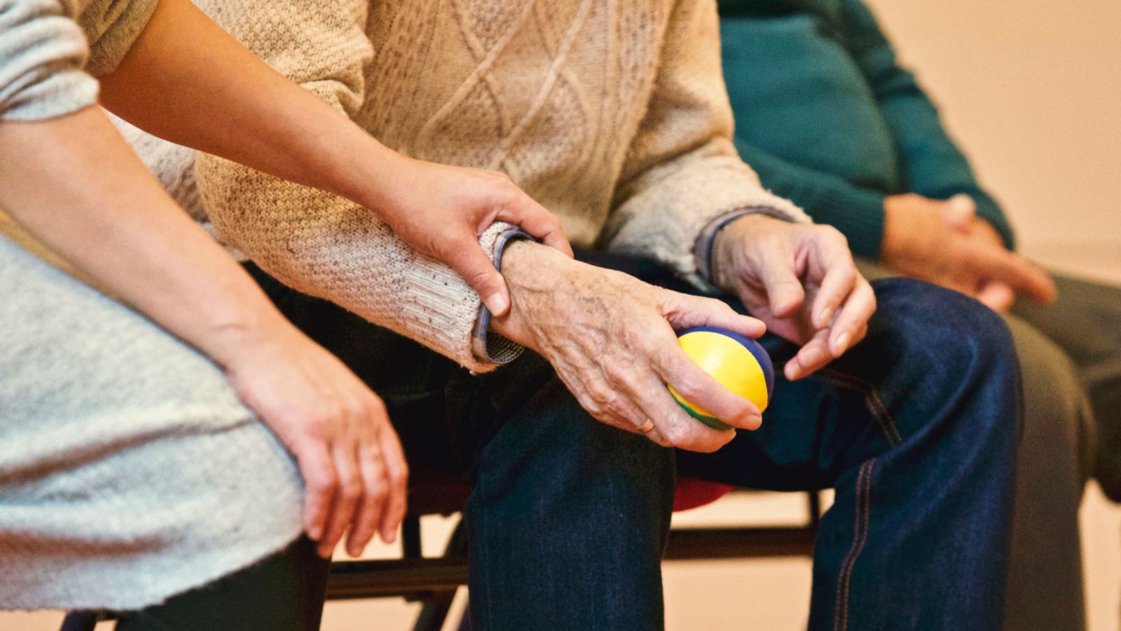 A volunteer's hand gently resting on the hand of an older person