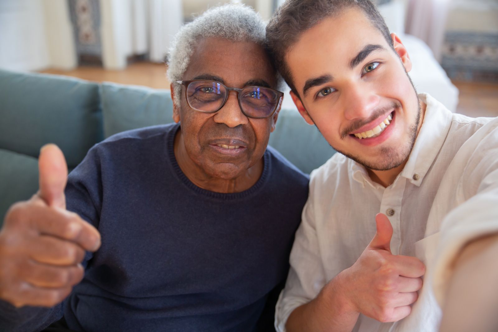 An older man and a young volunteer smiling together, giving a thumbs up