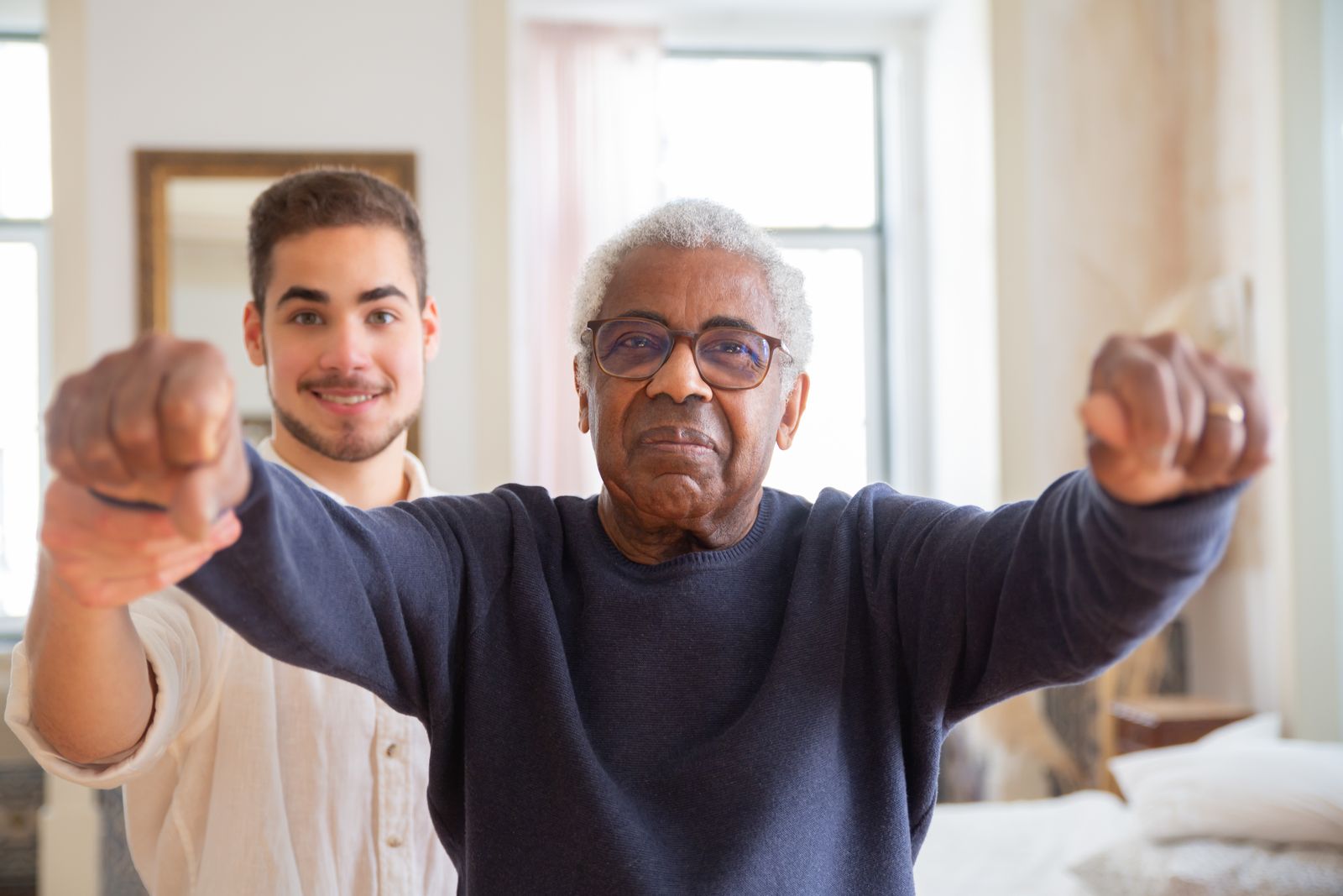 A volunteer guiding an older man through gentle seated exercises at home