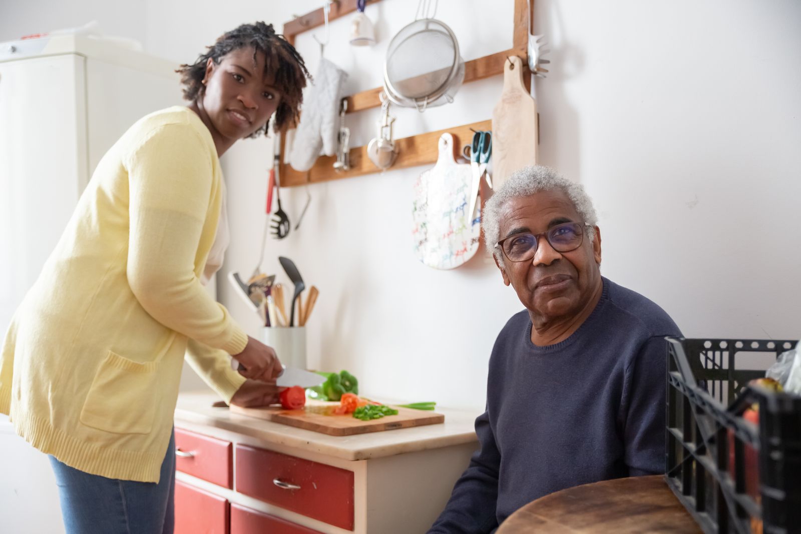 A volunteer preparing fresh vegetables in the kitchen of an older man