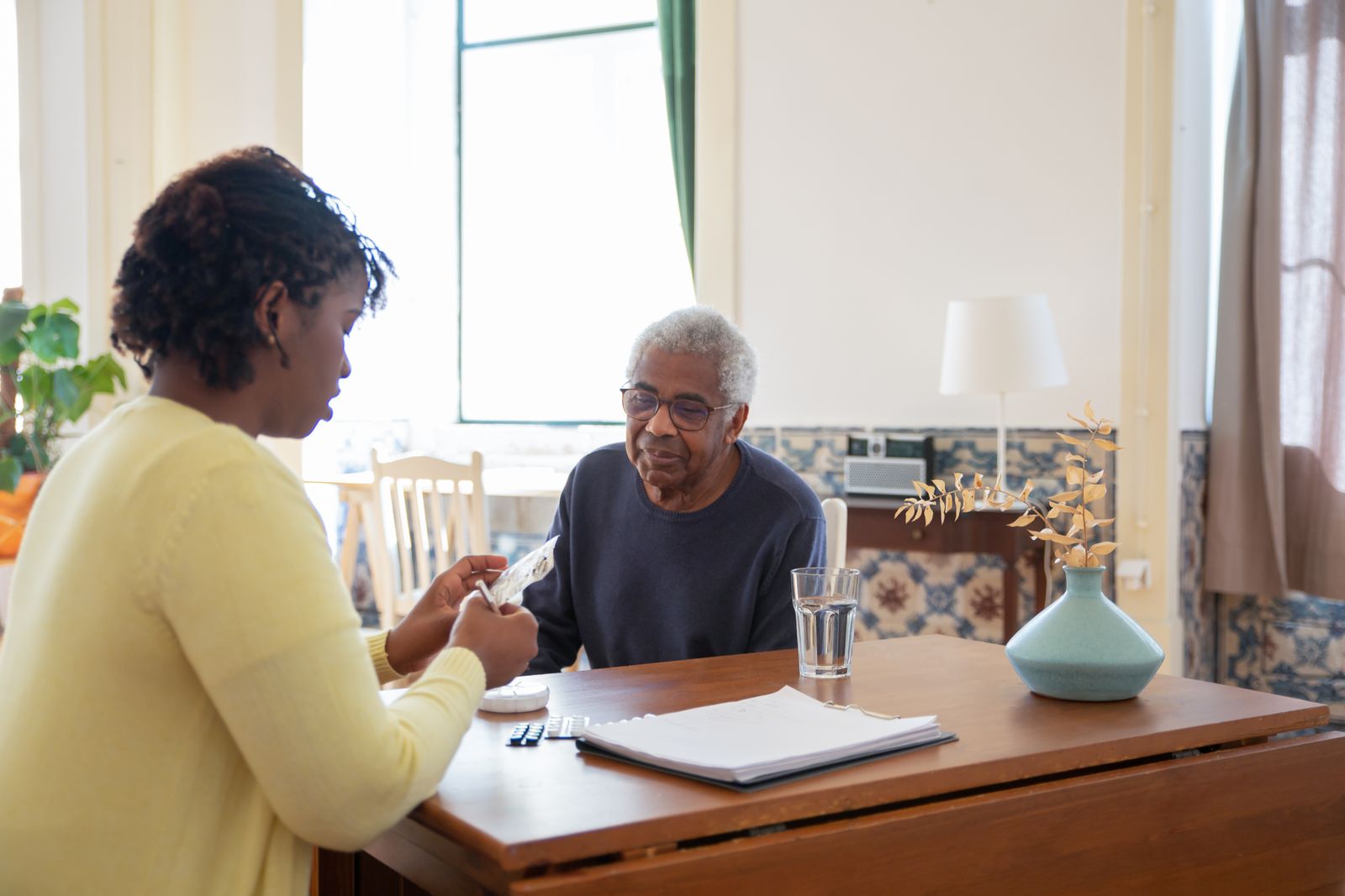 A volunteer helping an older man with official paperwork at his table
