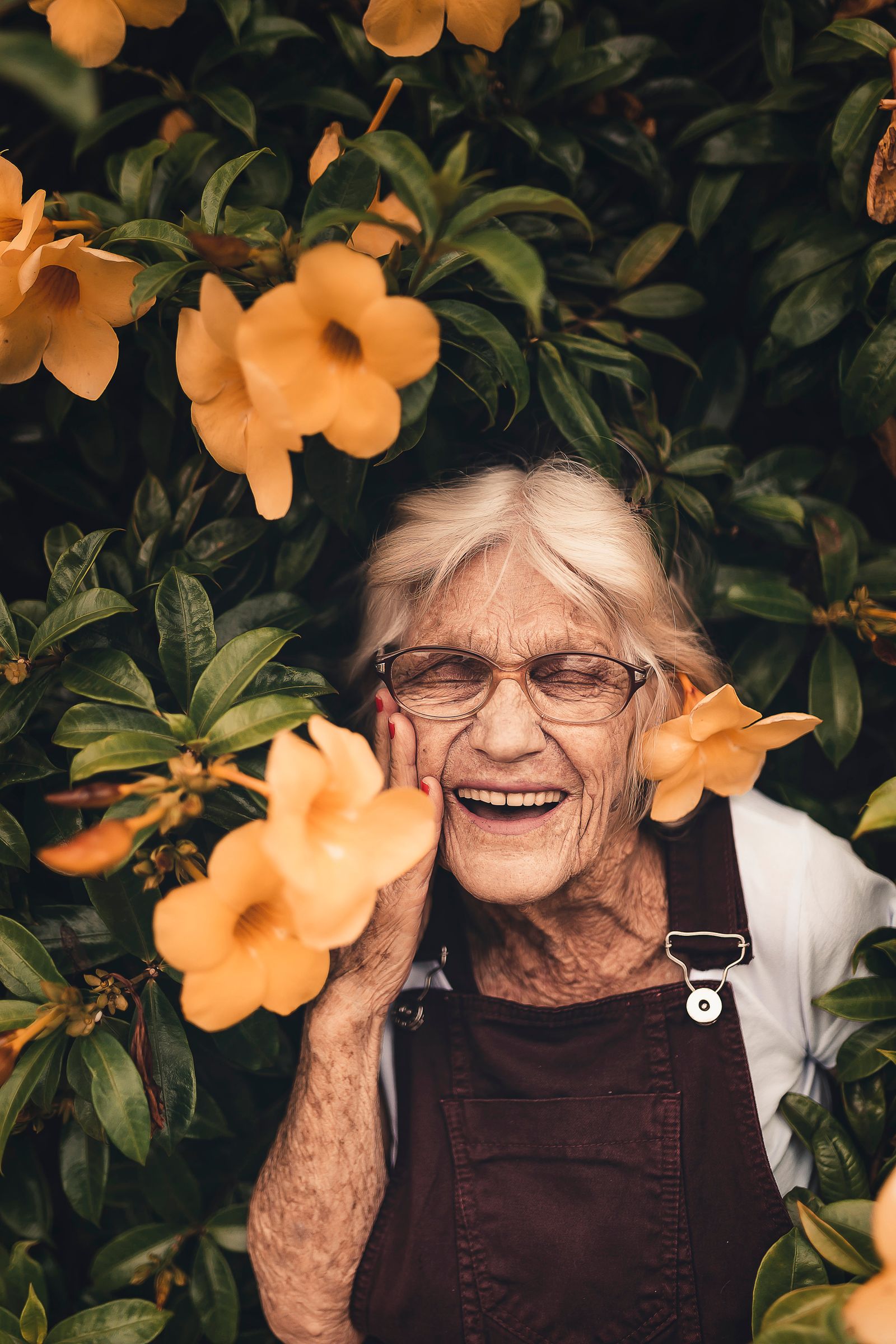 An older woman laughing joyfully, surrounded by flowers