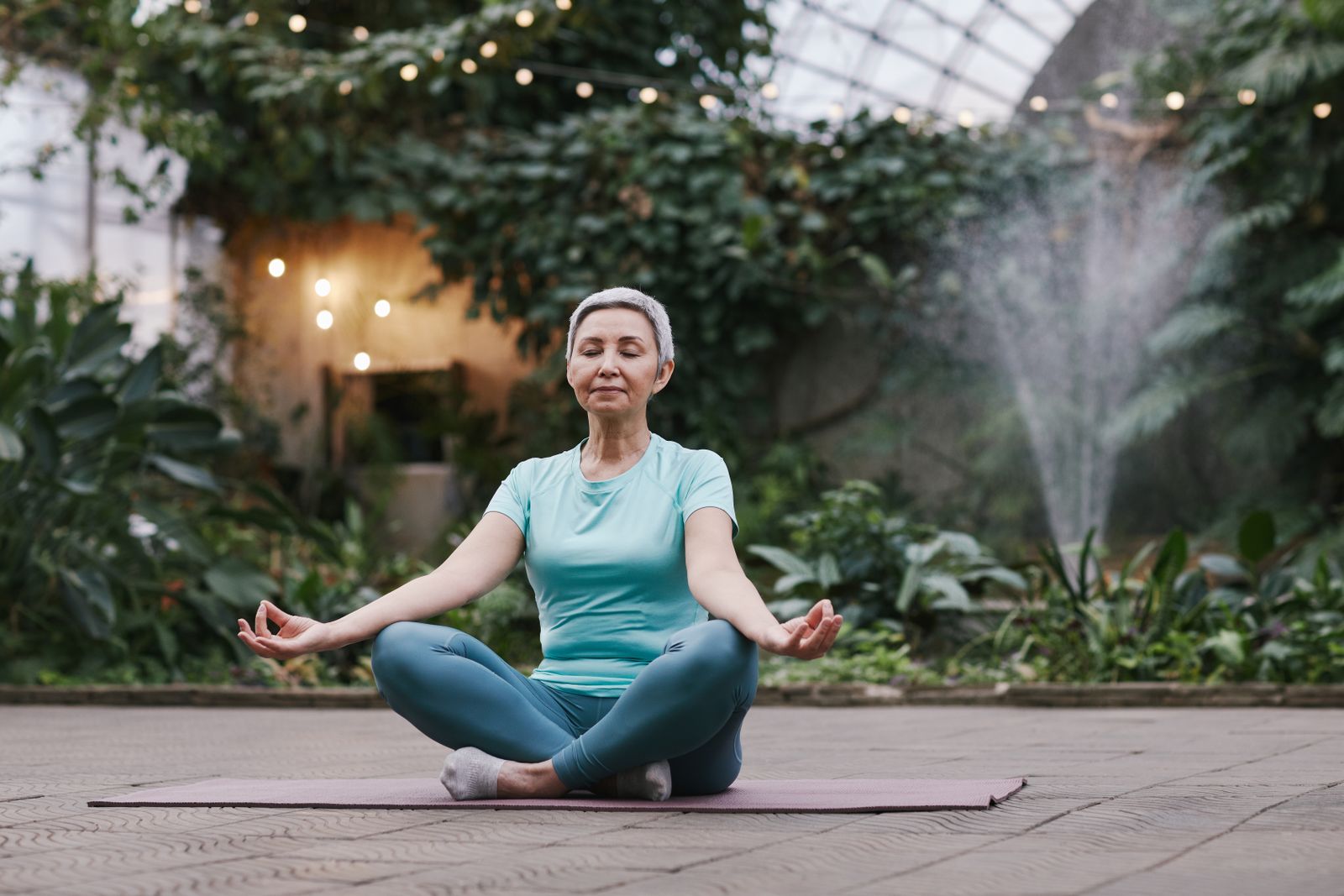 An older woman practising calm, gentle movement in a green setting